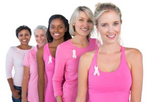 Smiling women wearing pink and ribbons for breast cancer on white background